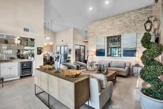 tiled living room with high vaulted ceiling, wine cooler, and indoor bar