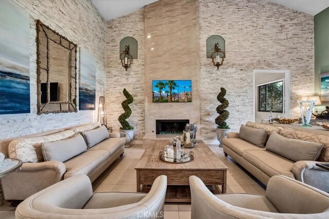 living room with high vaulted ceiling, light tile patterned flooring, and a large fireplace