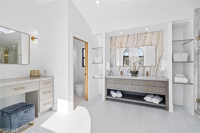 bathroom with a shower with door, built in shelves, vanity, and vaulted ceiling