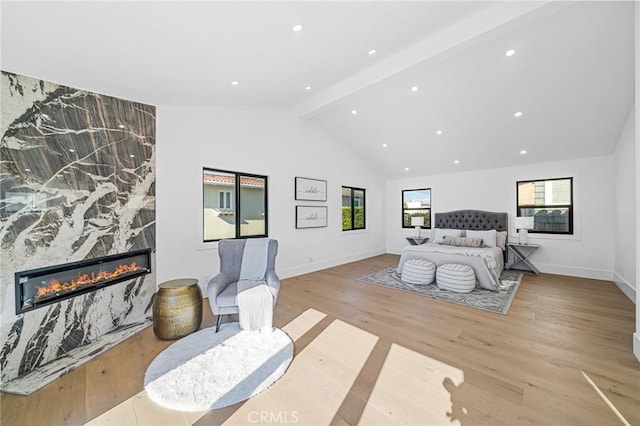 bedroom with light hardwood / wood-style floors, a fireplace, and lofted ceiling with beams