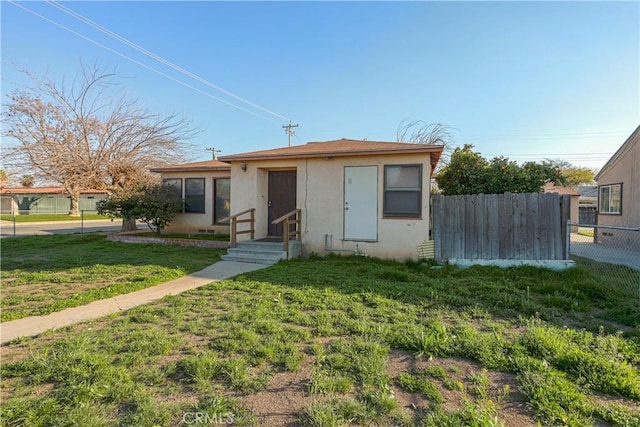 bungalow-style house featuring stucco siding, a front yard, and fence