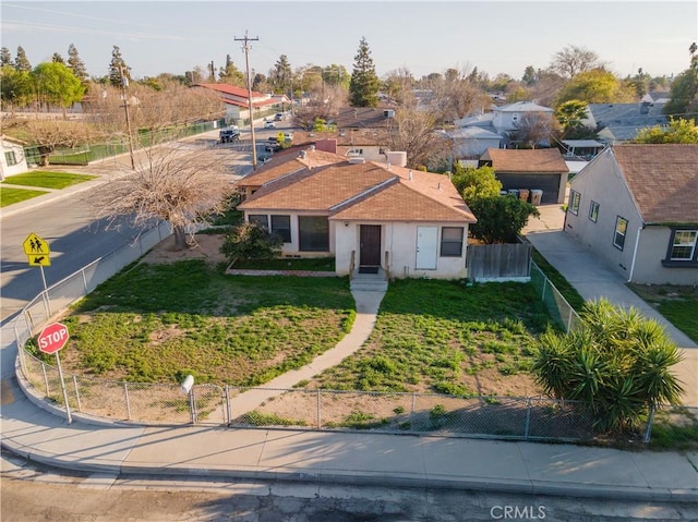 view of front facade featuring stucco siding, a residential view, fence private yard, and a front lawn