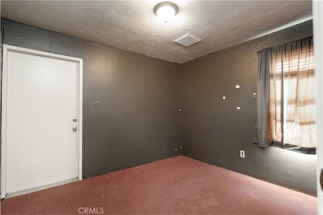 spare room featuring visible vents, carpet floors, and a textured ceiling