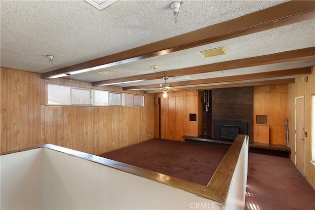 interior space featuring wooden walls, a fireplace, a textured ceiling, and carpet