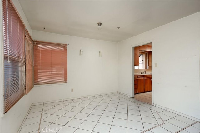 unfurnished room with light tile patterned floors and a sink