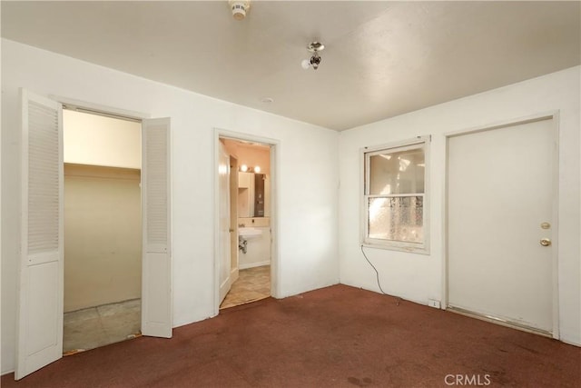 unfurnished bedroom featuring connected bathroom, carpet, and a closet