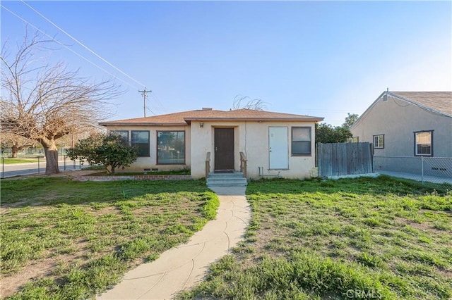 bungalow featuring a front yard, fence, and stucco siding