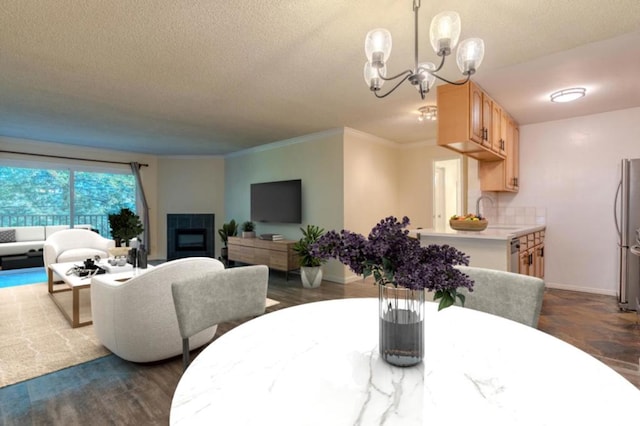 dining space featuring a textured ceiling, sink, a chandelier, a tile fireplace, and crown molding