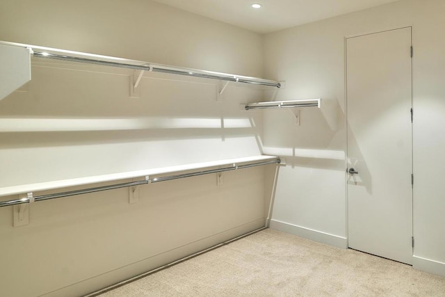 walk in closet with light colored carpet