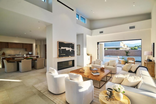 living room with sink, plenty of natural light, a towering ceiling, and a fireplace