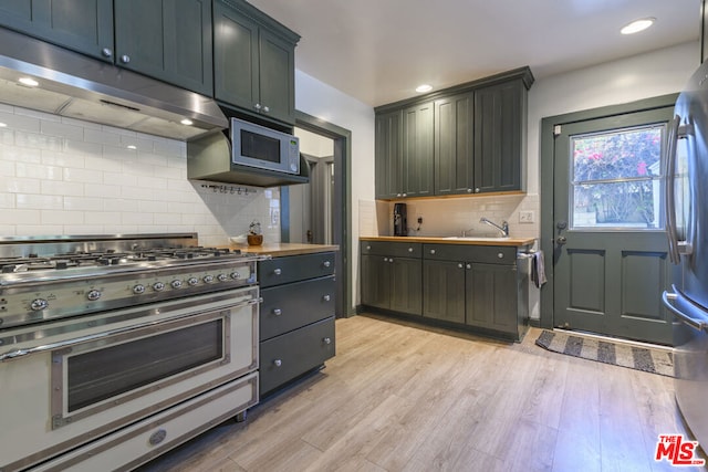 kitchen with stainless steel appliances, sink, tasteful backsplash, and light hardwood / wood-style flooring