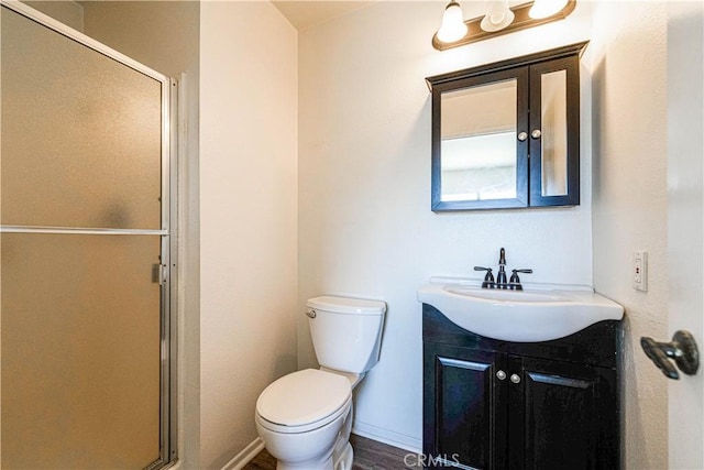 bathroom featuring toilet, an enclosed shower, and vanity