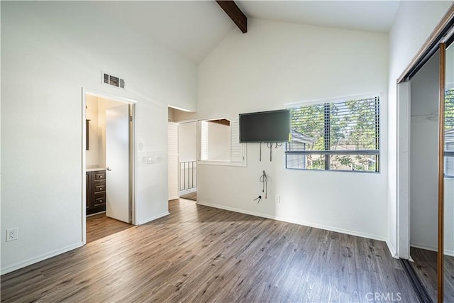 unfurnished bedroom featuring ensuite bathroom, beamed ceiling, hardwood / wood-style flooring, a closet, and high vaulted ceiling