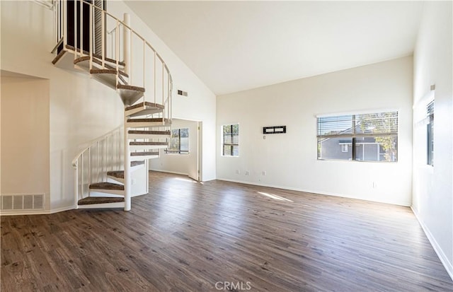 unfurnished living room featuring a healthy amount of sunlight, high vaulted ceiling, and dark hardwood / wood-style floors