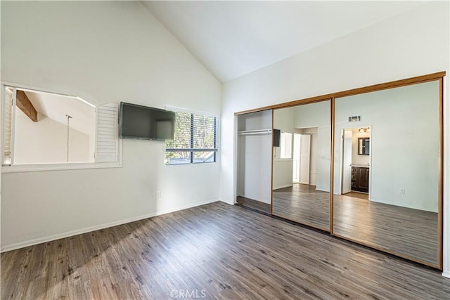 unfurnished bedroom with a closet, dark wood-type flooring, high vaulted ceiling, beam ceiling, and ensuite bathroom