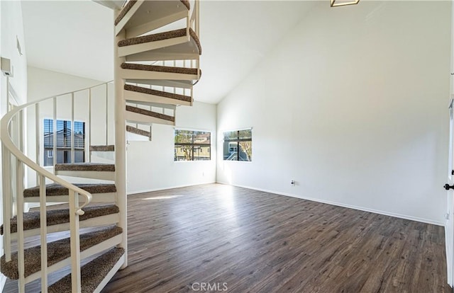 unfurnished living room with high vaulted ceiling and dark hardwood / wood-style flooring