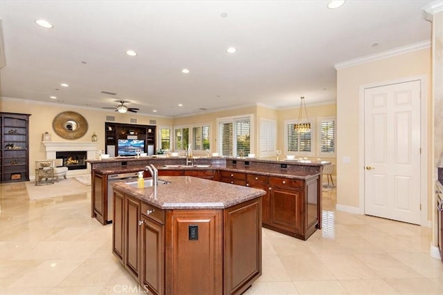 kitchen with a spacious island, recessed lighting, a lit fireplace, brown cabinetry, and stone counters