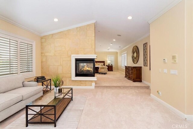 living room with crown molding, baseboards, a multi sided fireplace, and light carpet