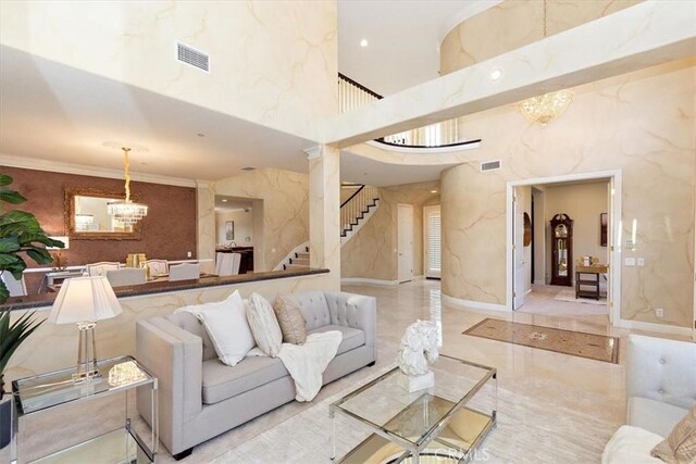 living area with stairs, an inviting chandelier, a high ceiling, and visible vents