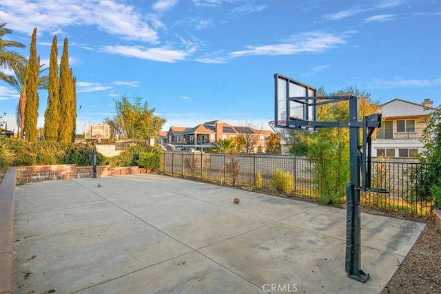 view of sport court featuring a residential view, basketball court, and fence