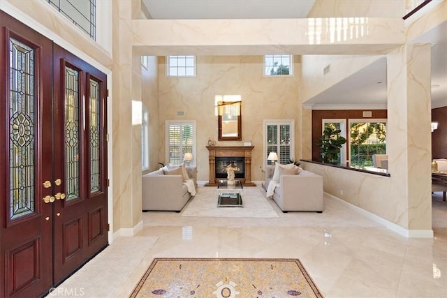 foyer with a premium fireplace, baseboards, marble finish floor, and a towering ceiling