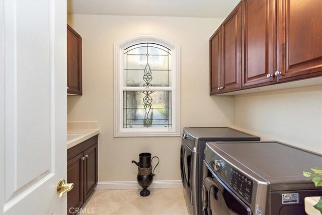 washroom featuring cabinet space, light tile patterned floors, independent washer and dryer, and baseboards