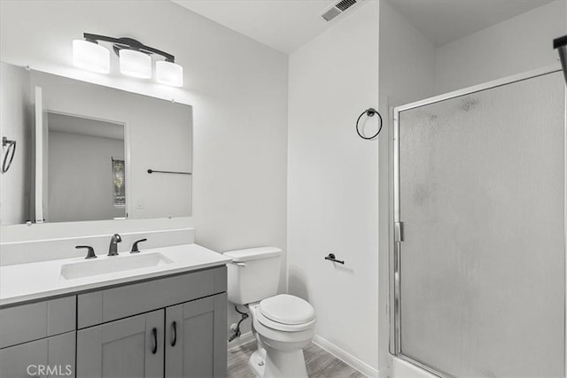 bathroom featuring hardwood / wood-style floors, vanity, toilet, and a shower with shower door