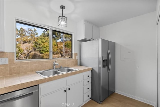 kitchen with sink, pendant lighting, stainless steel appliances, decorative backsplash, and white cabinets