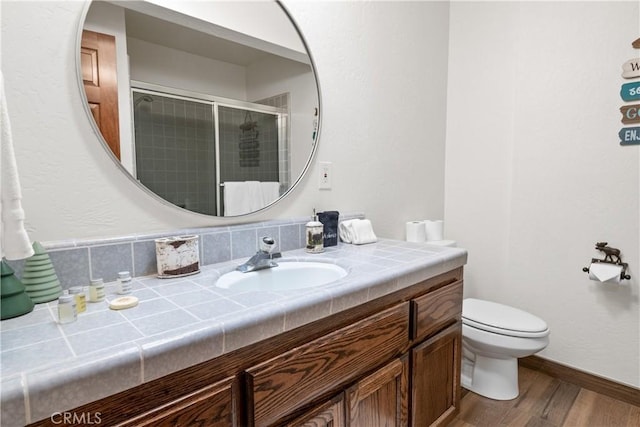 bathroom with toilet, an enclosed shower, vanity, and hardwood / wood-style floors