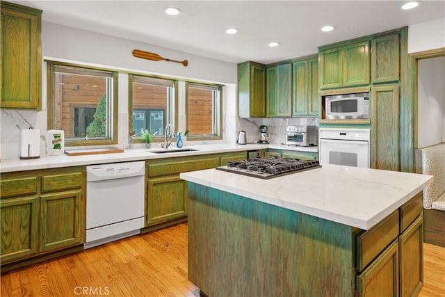 kitchen featuring white appliances, sink, backsplash, and a center island