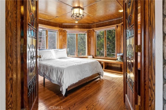 bedroom with wood walls, wood-type flooring, and wood ceiling