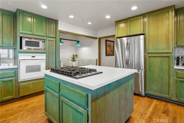 kitchen featuring stainless steel appliances, light wood-type flooring, green cabinetry, and a kitchen island