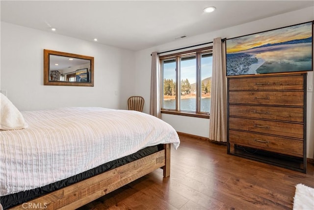 bedroom featuring dark wood-type flooring and a water view