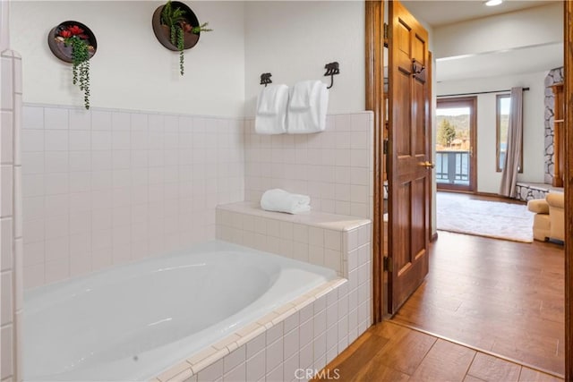 bathroom featuring hardwood / wood-style flooring and a relaxing tiled tub