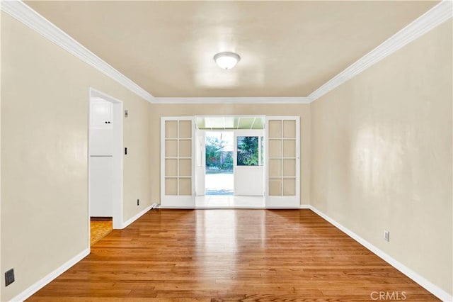 empty room featuring hardwood / wood-style floors, crown molding, and french doors