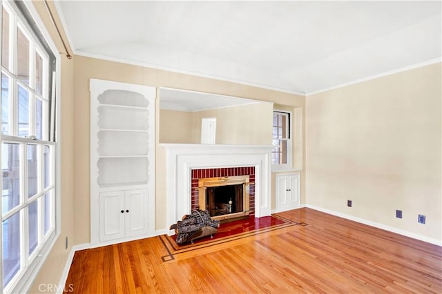 unfurnished living room featuring wood-type flooring, crown molding, and a fireplace