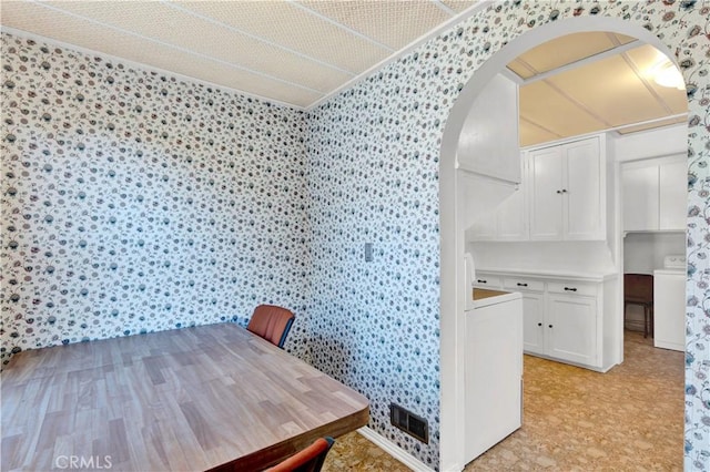 dining space featuring washer / dryer, ornamental molding, and light hardwood / wood-style floors