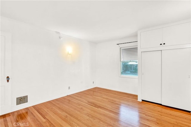 unfurnished bedroom with light hardwood / wood-style flooring and a closet