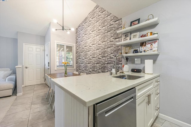 kitchen with sink, white cabinetry, stainless steel dishwasher, light stone countertops, and a chandelier