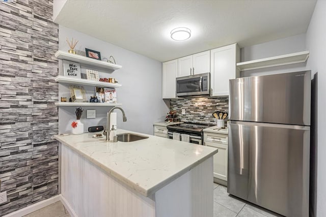 kitchen featuring light stone countertops, stainless steel appliances, white cabinets, light tile patterned flooring, and sink