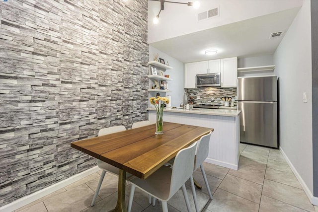 kitchen featuring stainless steel appliances, light tile patterned floors, white cabinets, and tasteful backsplash