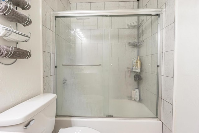 bathroom with combined bath / shower with glass door and toilet