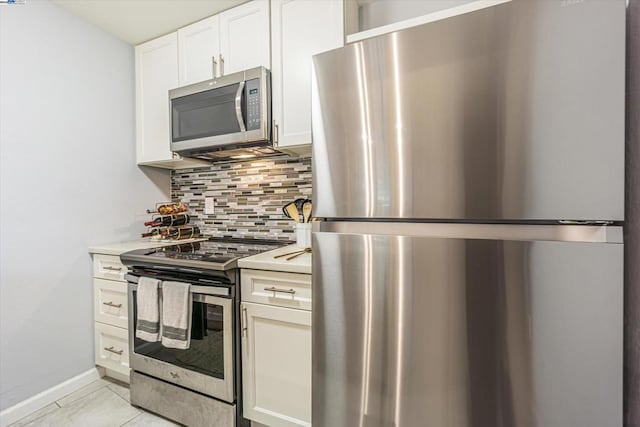 kitchen featuring appliances with stainless steel finishes, white cabinetry, decorative backsplash, and light tile patterned floors