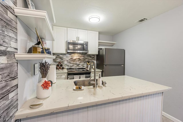 kitchen with light stone counters, stainless steel appliances, tasteful backsplash, white cabinetry, and sink