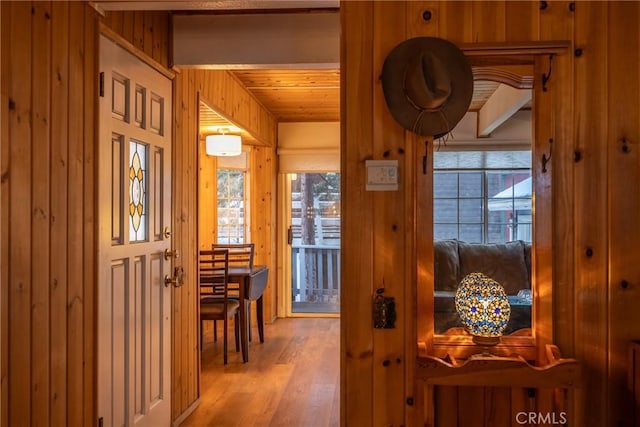 corridor with wood ceiling, wooden walls, light hardwood / wood-style floors, and plenty of natural light