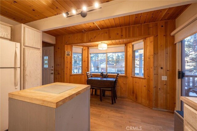 kitchen with white fridge, track lighting, wood walls, and butcher block counters