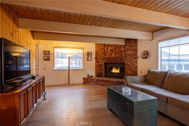 living room featuring wooden walls, hardwood / wood-style floors, beamed ceiling, a fireplace, and wooden ceiling