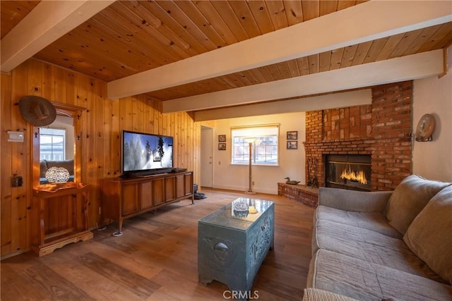 living room featuring beamed ceiling, wooden ceiling, wood walls, and a fireplace