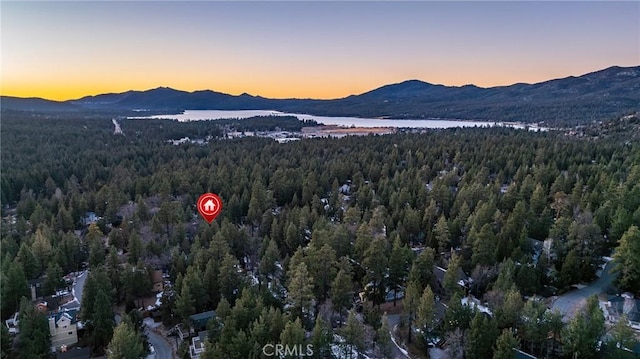 aerial view at dusk featuring a water and mountain view