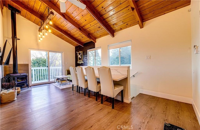 dining space featuring a wood stove, wood ceiling, and a healthy amount of sunlight